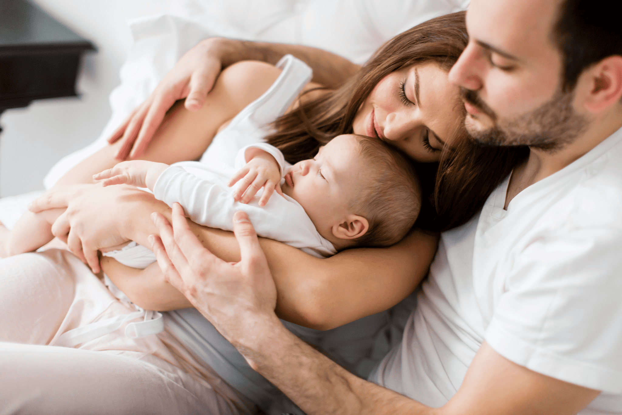 Eltern liegen mit Baby harmonisch auf dem Sofa
