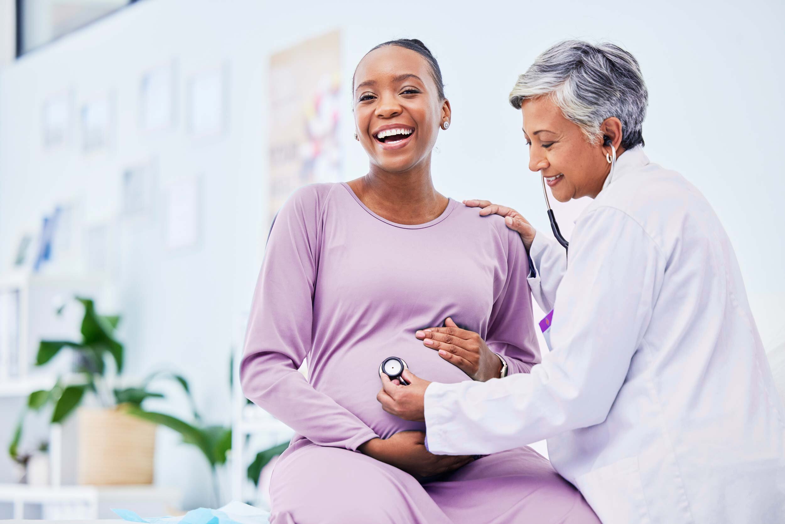 Eine schwangere Frau sitzt beim Frauenarzt in der Vorsorgeuntersuchung