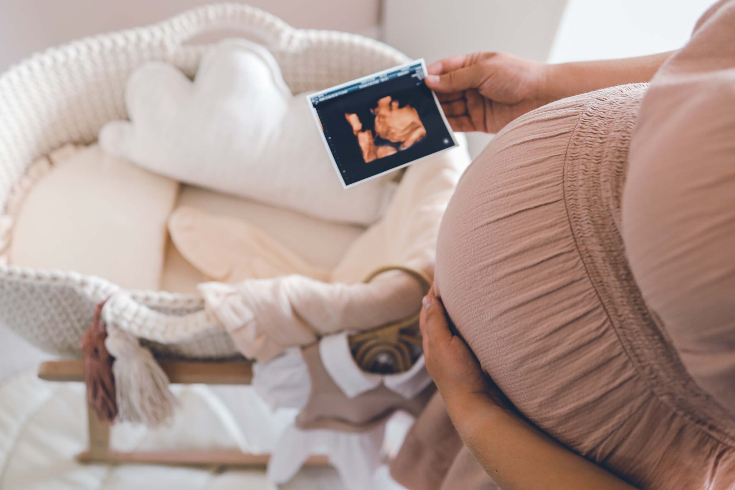 Schwangere Mutter hält ein Ultraschallbild aus der Vorsorgeuntersuchung in der Hand