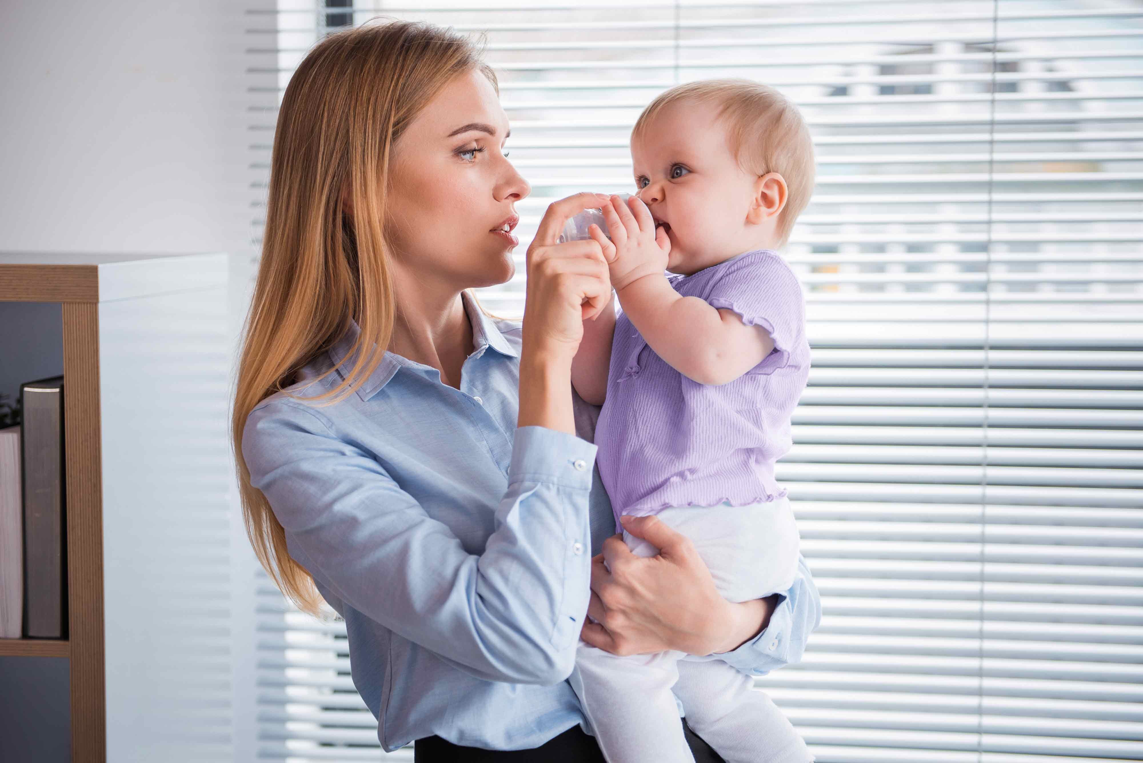 Eine Mutter füttert im Büro ihr Baby mit der Flasche