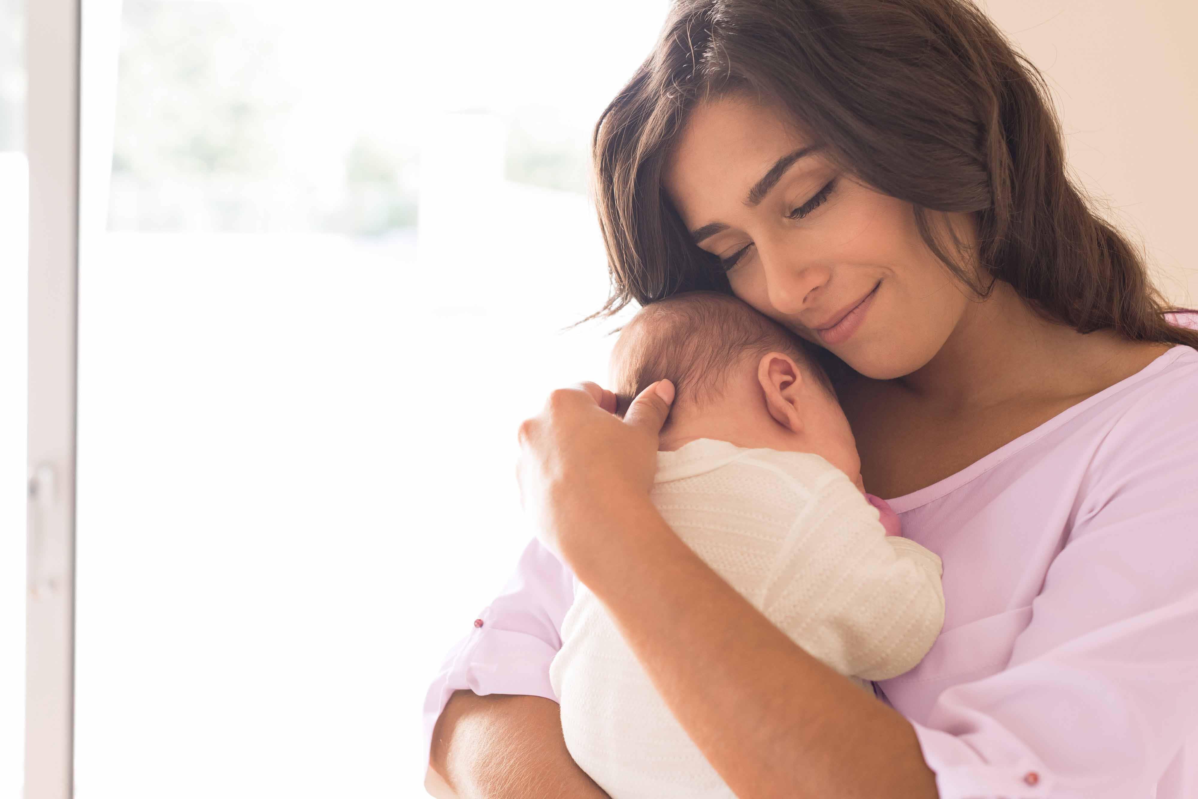 Mutter hält neugeborenes Baby im Arm