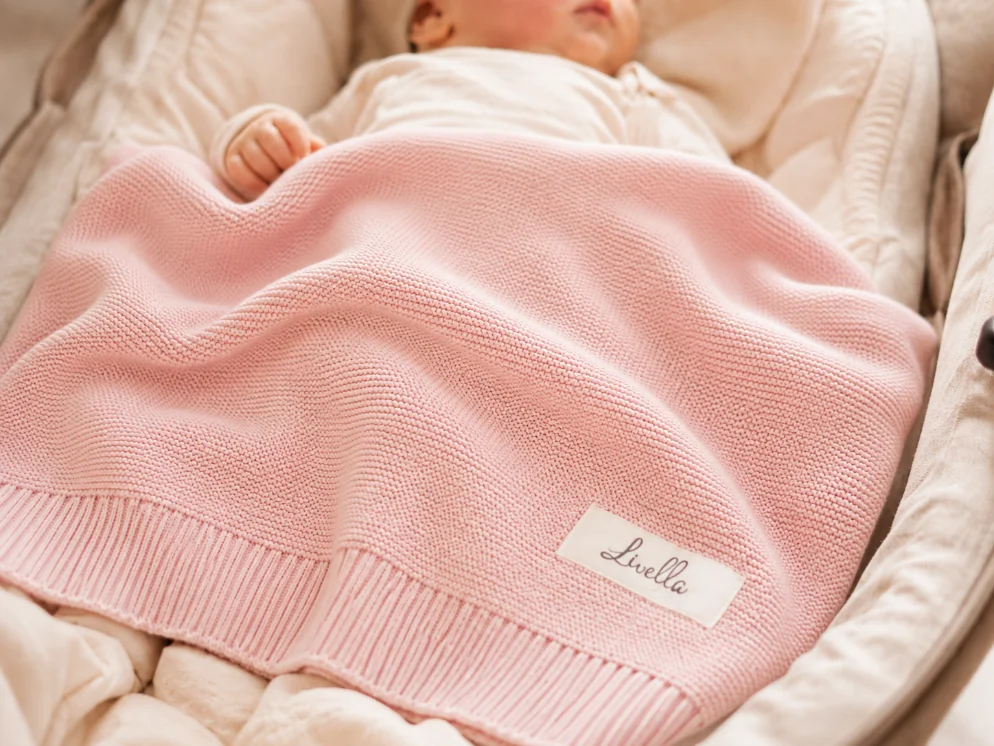 Baby unter einer rosa Livella Babydecke